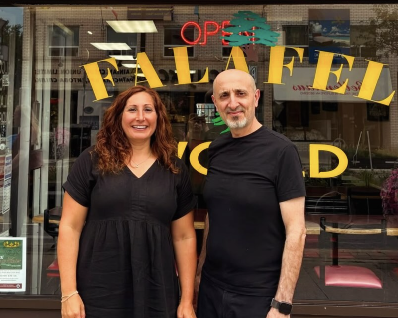 Nadia standing in front of Falafel World with the owner